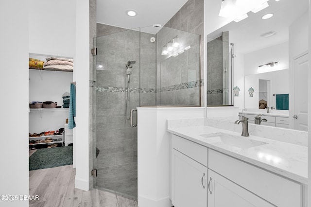 802 Margaritaville Ave, Daytona Beach, FL 32124 - bathroom with a shower stall, a walk in closet, wood finished floors, vanity, and recessed lighting