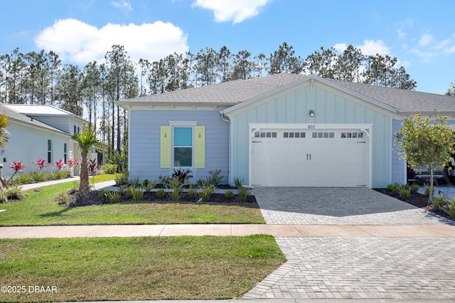 802 Margaritaville Ave, Daytona Beach, FL 32124 - ranch-style house with board and batten siding, decorative driveway, an attached garage, a front lawn, and a shingled roof