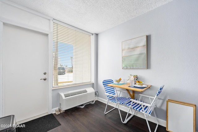 interior space featuring a wall mounted air conditioner, dark wood finished floors, a textured ceiling, and baseboards