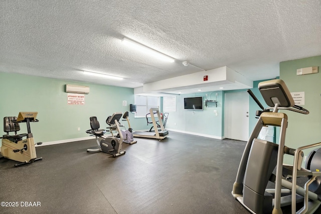 workout area with a textured ceiling, a wall mounted AC, and baseboards