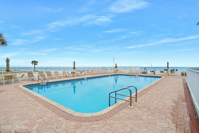 pool featuring a water view, fence, and a patio