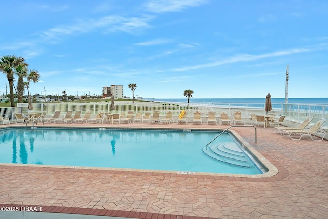 community pool featuring a water view, a patio area, and fence