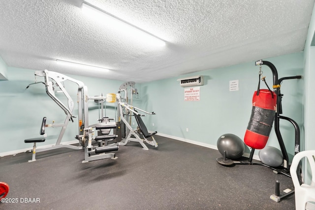 workout area featuring a textured ceiling, a wall unit AC, and baseboards