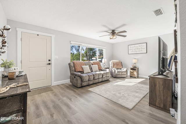 living room featuring a textured ceiling, light hardwood / wood-style flooring, and ceiling fan