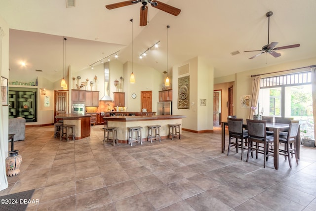 dining space featuring track lighting, ceiling fan, high vaulted ceiling, and light tile patterned floors