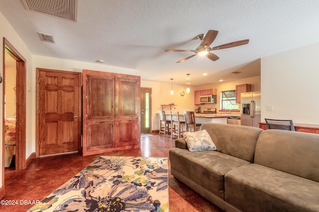 living room featuring ceiling fan and a textured ceiling