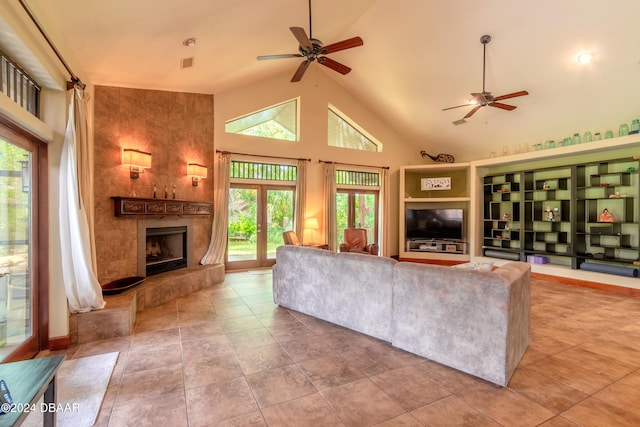 living room featuring high vaulted ceiling, a tiled fireplace, ceiling fan, and tile patterned floors