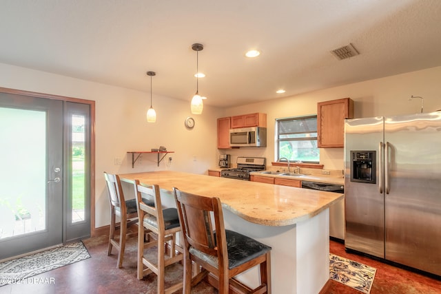 kitchen featuring stainless steel appliances, sink, kitchen peninsula, a kitchen bar, and pendant lighting