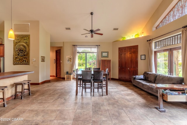 tiled dining space with high vaulted ceiling and ceiling fan