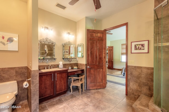 bathroom with tile walls, vanity, tile patterned flooring, toilet, and ceiling fan