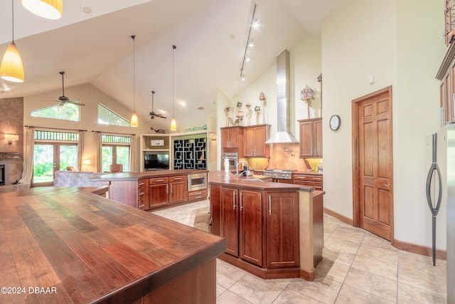 kitchen featuring stainless steel appliances, a center island, kitchen peninsula, wall chimney exhaust hood, and high vaulted ceiling