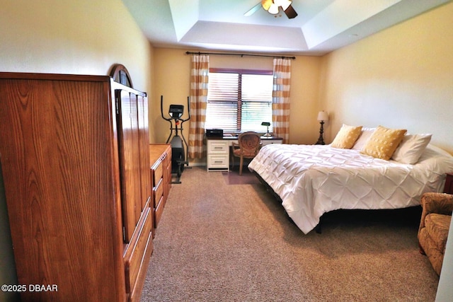 carpeted bedroom featuring ceiling fan and a raised ceiling