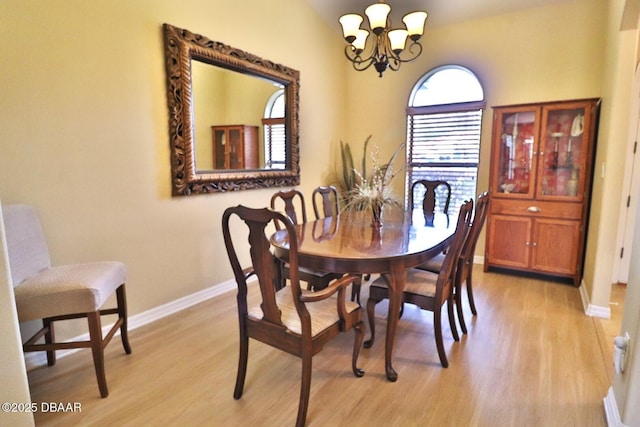 dining space with light hardwood / wood-style flooring and a notable chandelier