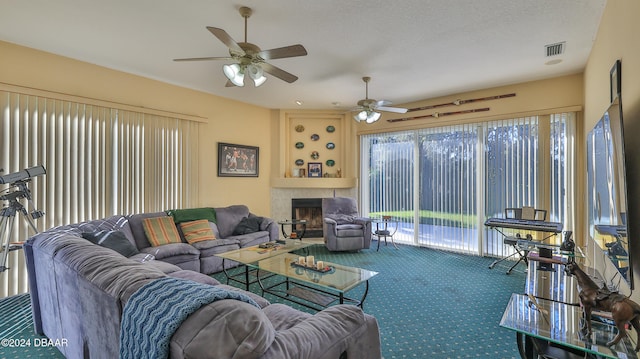 carpeted living room featuring ceiling fan, a textured ceiling, and a tiled fireplace