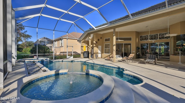 view of swimming pool featuring ceiling fan, glass enclosure, an in ground hot tub, and a patio area