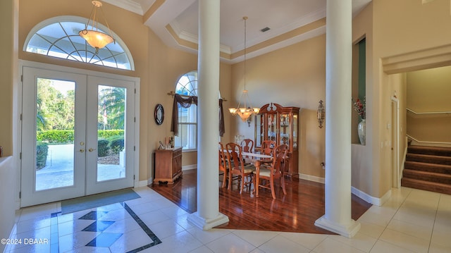 entryway featuring french doors, a towering ceiling, a notable chandelier, crown molding, and light hardwood / wood-style flooring