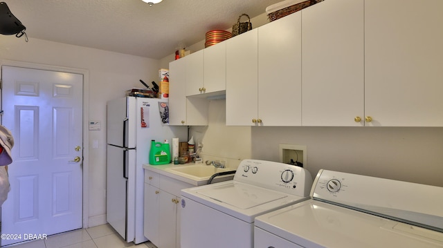 washroom featuring cabinets, light tile patterned floors, a textured ceiling, sink, and washing machine and clothes dryer