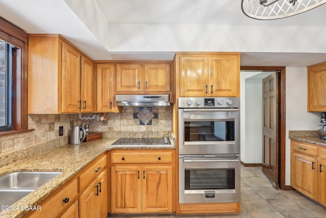 kitchen with black electric stovetop, light tile patterned floors, stainless steel double oven, backsplash, and light stone countertops