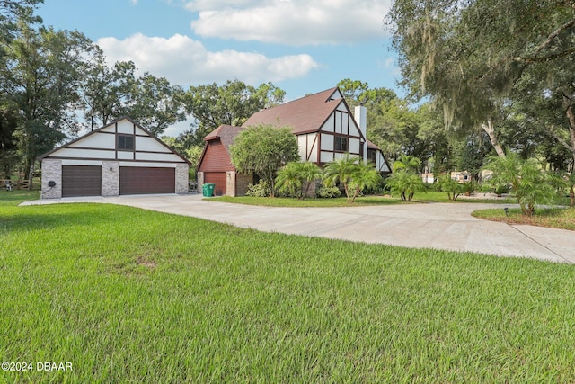 tudor house with a garage, an outdoor structure, and a front yard