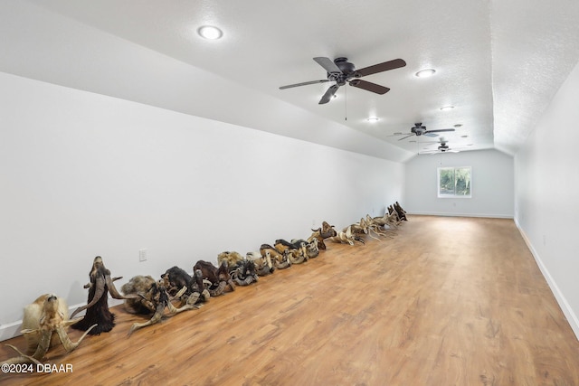 additional living space with ceiling fan, a textured ceiling, light wood-type flooring, and vaulted ceiling