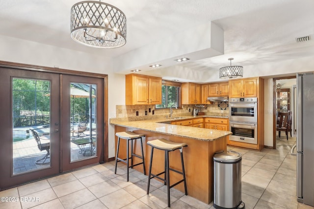 kitchen featuring a healthy amount of sunlight, kitchen peninsula, sink, and decorative light fixtures