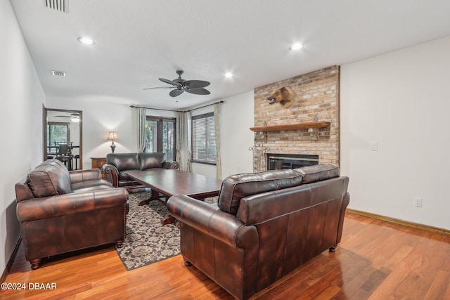 living room featuring a fireplace, ceiling fan, and light hardwood / wood-style flooring