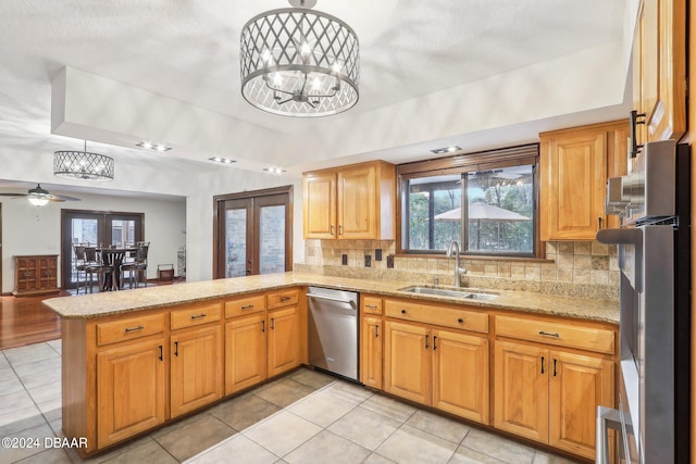 kitchen featuring sink, kitchen peninsula, appliances with stainless steel finishes, backsplash, and french doors