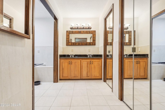 bathroom featuring tiled bath, tile patterned flooring, and vanity