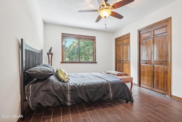 bedroom with a textured ceiling, dark wood-type flooring, and ceiling fan