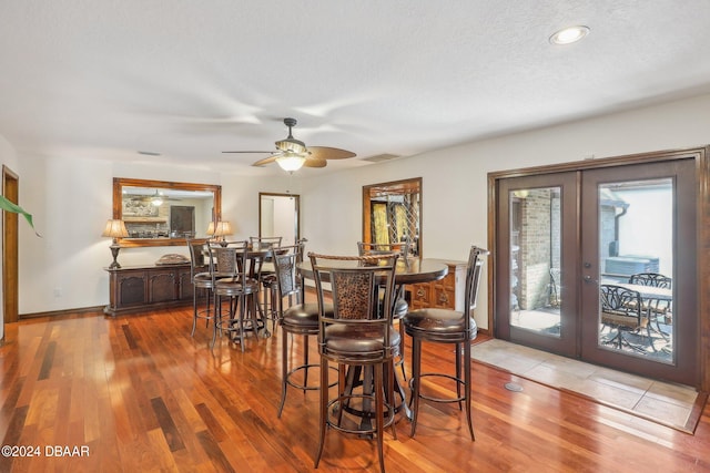 dining area featuring ceiling fan, french doors, light hardwood / wood-style floors, and a textured ceiling