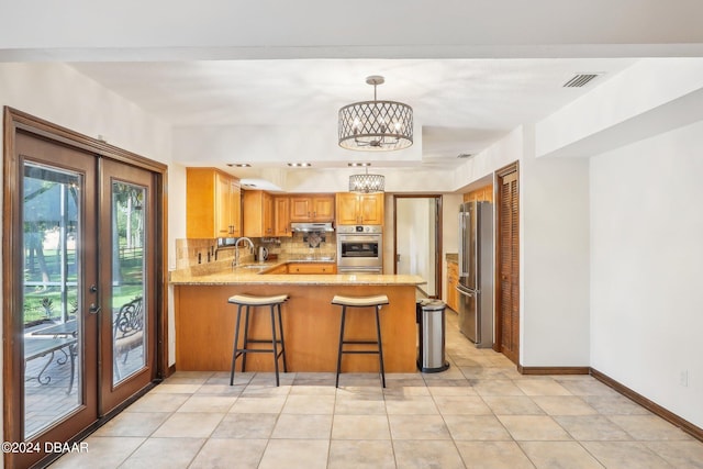 kitchen featuring a kitchen bar, kitchen peninsula, sink, pendant lighting, and appliances with stainless steel finishes