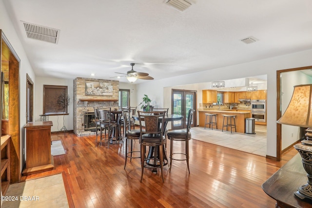 dining room featuring ceiling fan, light hardwood / wood-style floors, and a fireplace