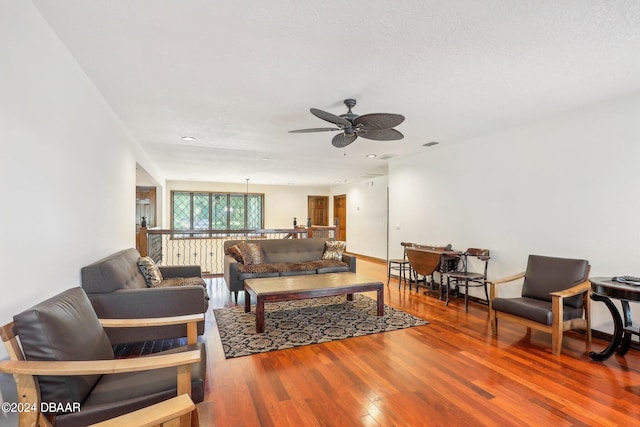 living room featuring wood-type flooring, ceiling fan, and a textured ceiling