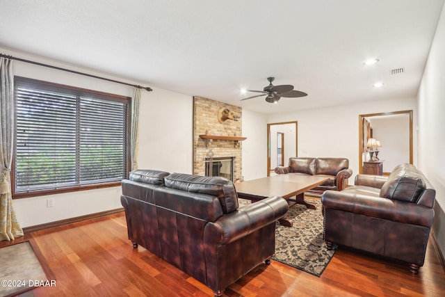 living room featuring hardwood / wood-style flooring, ceiling fan, and a fireplace