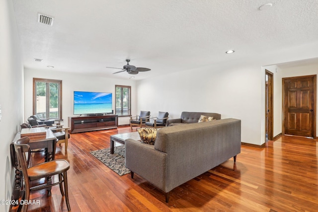 living room with a textured ceiling, hardwood / wood-style flooring, and ceiling fan