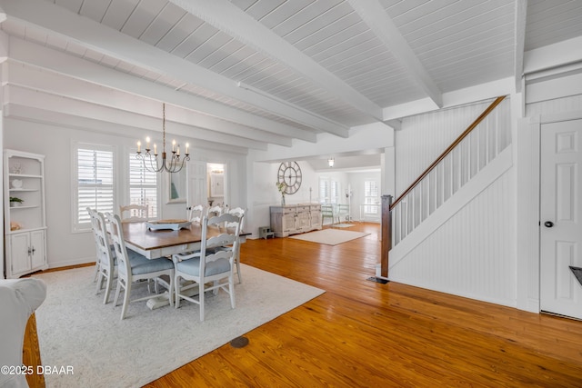 dining room with stairway, hardwood / wood-style flooring, a chandelier, baseboards, and beamed ceiling