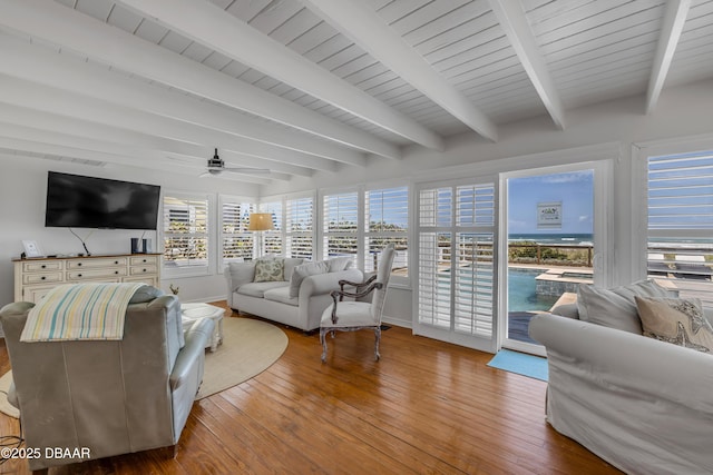 living room with beam ceiling, a ceiling fan, hardwood / wood-style flooring, and baseboards