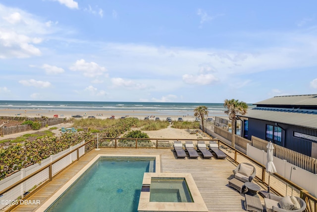 view of swimming pool with a deck with water view, a fenced in pool, and a beach view