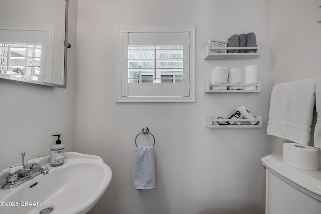 bathroom featuring toilet, a sink, and a healthy amount of sunlight