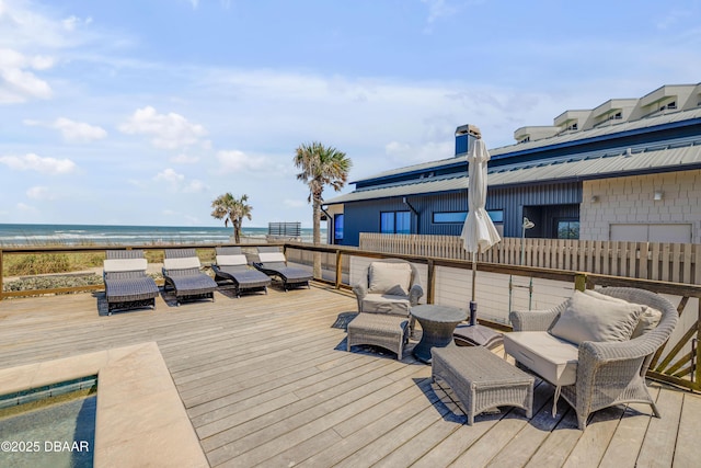 wooden deck featuring an outdoor hangout area, a water view, and a view of the beach