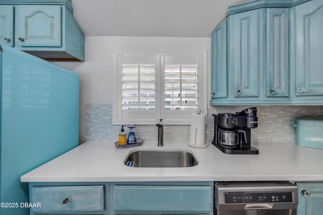 kitchen with fridge, blue cabinets, backsplash, a sink, and dishwasher