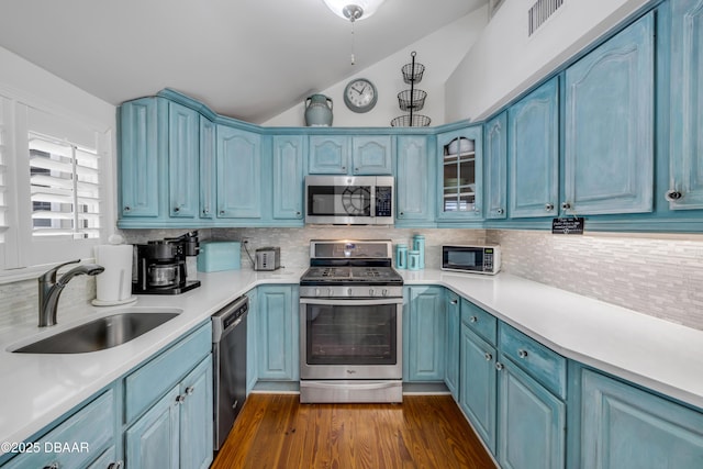 kitchen with visible vents, appliances with stainless steel finishes, a sink, blue cabinets, and vaulted ceiling