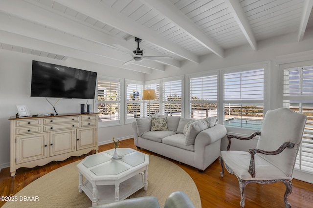 living area featuring baseboards, beam ceiling, wood finished floors, and ceiling fan