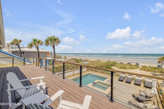 wooden deck featuring a water view, an in ground hot tub, and a beach view
