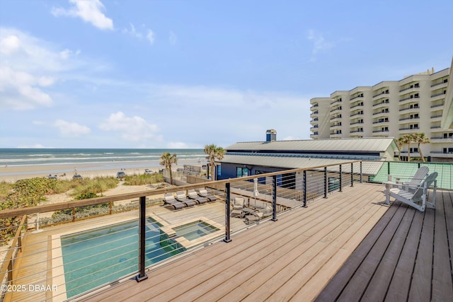 wooden terrace featuring a beach view and a water view