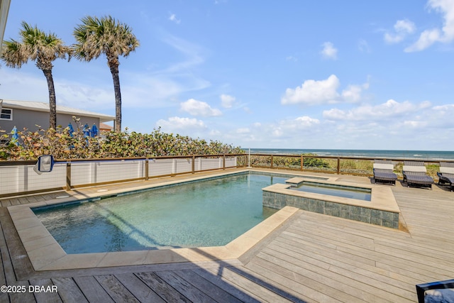 view of pool with a deck with water view and a pool with connected hot tub