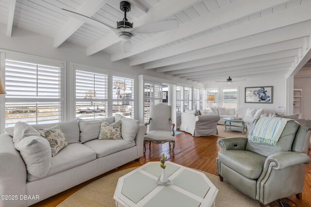 living room with beamed ceiling, wood finished floors, and a ceiling fan