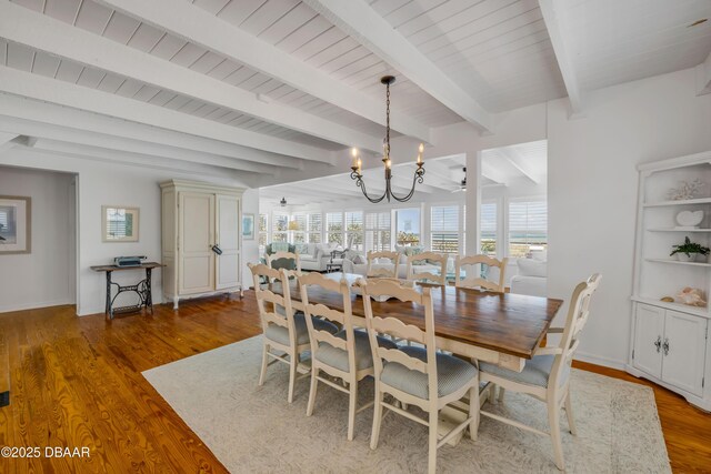 dining space featuring beam ceiling, baseboards, a chandelier, and wood finished floors