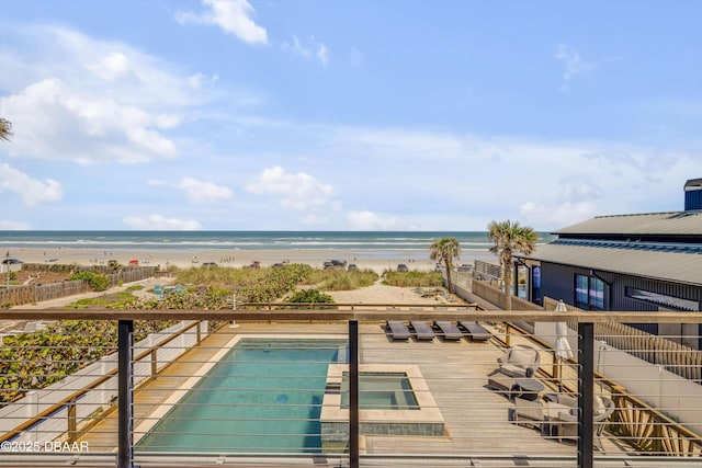 outdoor pool featuring a beach view, fence, and a deck with water view
