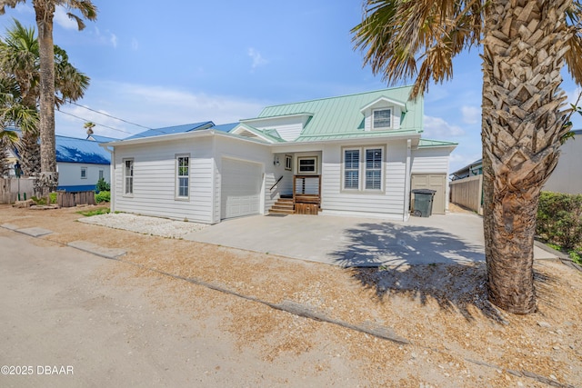 view of front facade with fence, metal roof, a garage, and concrete driveway